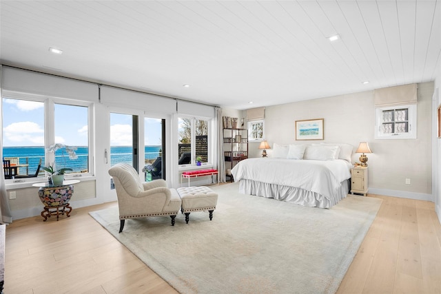 bedroom featuring recessed lighting, light wood-style flooring, a water view, and access to exterior