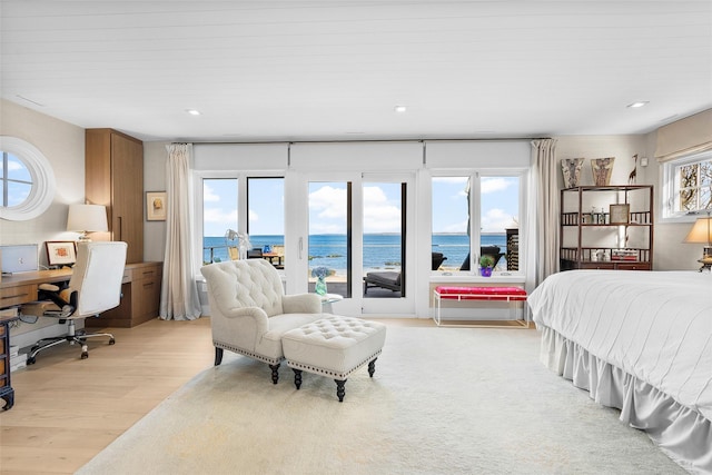bedroom with recessed lighting, a water view, light wood-type flooring, and access to exterior