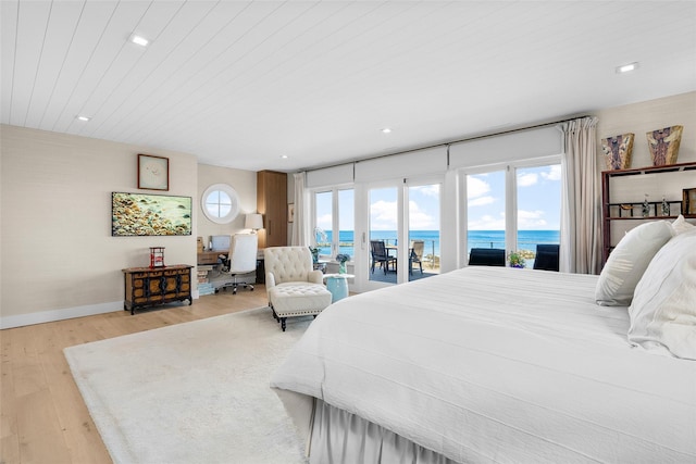 bedroom with access to exterior, light wood-style flooring, recessed lighting, baseboards, and a water view