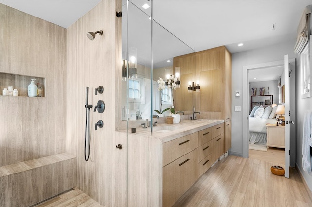 bathroom featuring a sink, connected bathroom, wood finished floors, and tiled shower