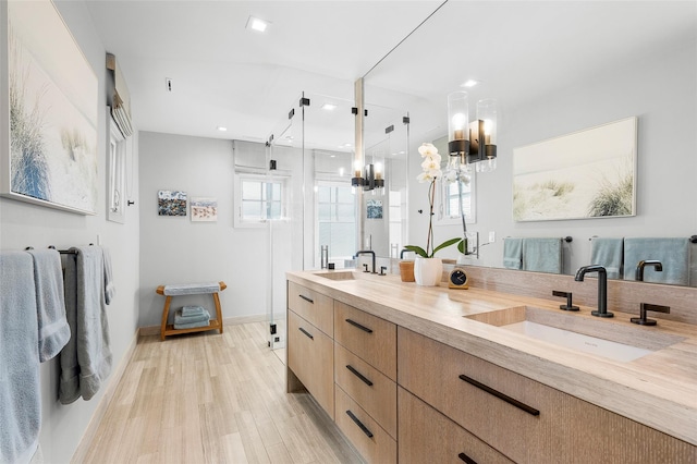full bath featuring a sink, a shower stall, double vanity, and a wealth of natural light