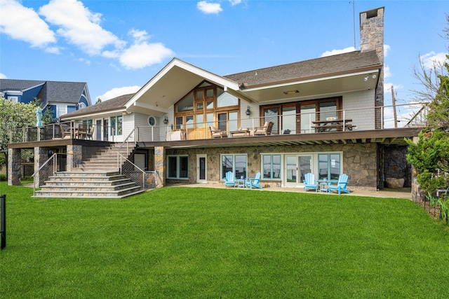 back of house featuring stone siding, stairway, a chimney, a balcony, and a yard