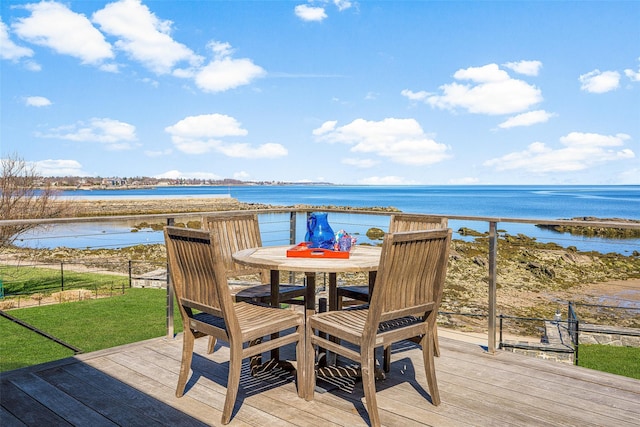 deck featuring fence, outdoor dining space, a water view, and a yard