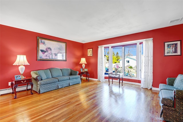 living area featuring visible vents, baseboards, baseboard heating, and wood finished floors