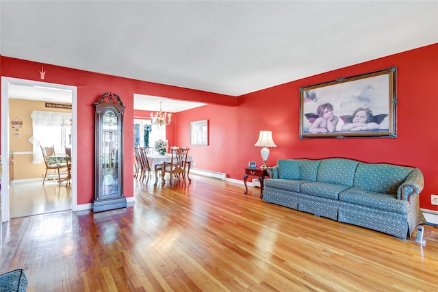 living area featuring baseboards, hardwood / wood-style floors, a chandelier, and a baseboard heating unit