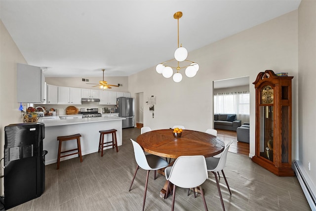 dining area featuring a baseboard heating unit, vaulted ceiling, a ceiling fan, and visible vents