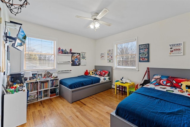 bedroom featuring wood finished floors, ceiling fan, and multiple windows