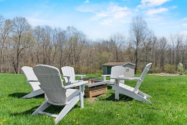 view of yard featuring an outdoor structure, a shed, a view of trees, and an outdoor fire pit