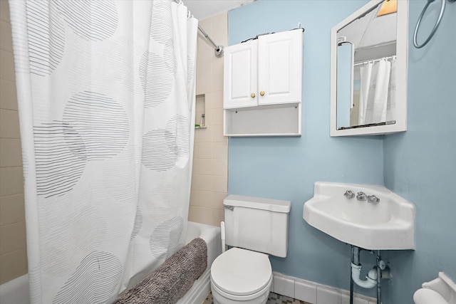 full bath featuring toilet, shower / bath combo with shower curtain, and baseboards