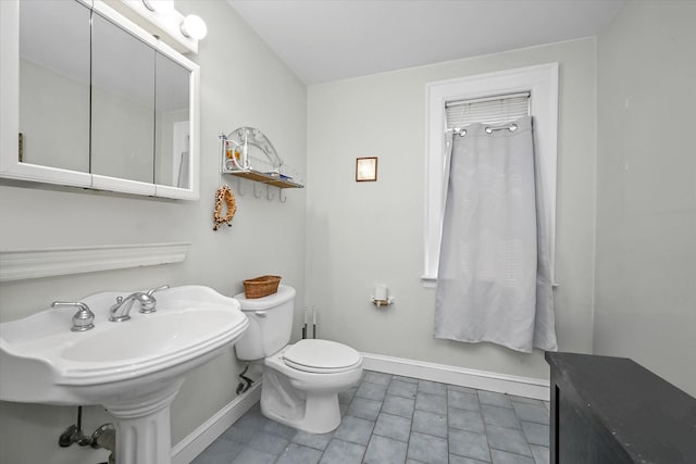 bathroom with toilet, baseboards, tile patterned flooring, and a sink