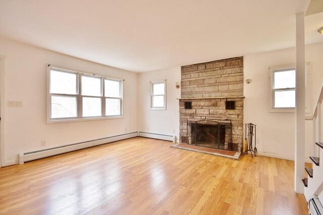 9 Old Albany Post Rd N, Cold Spring, NY 10516 - unfurnished living room with a baseboard heating unit, a stone fireplace, wood finished floors, and stairs