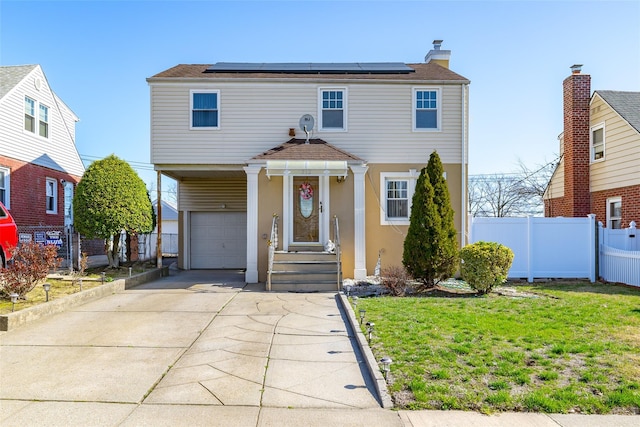 view of front facade featuring an attached garage, fence, solar panels, and concrete driveway