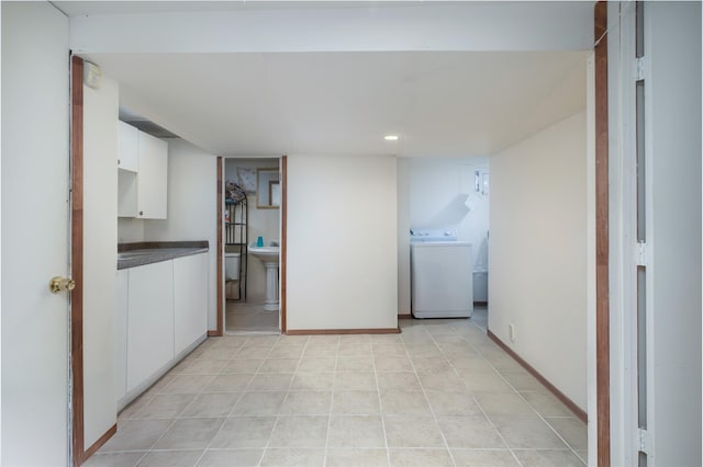 finished below grade area with washer / clothes dryer, baseboards, and light tile patterned flooring