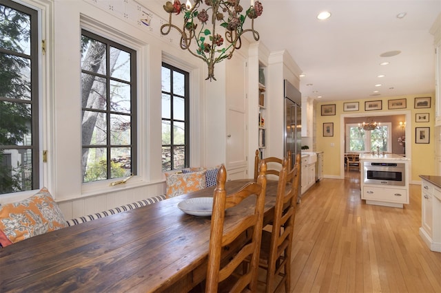 dining space featuring light wood-type flooring, recessed lighting, a chandelier, and a healthy amount of sunlight