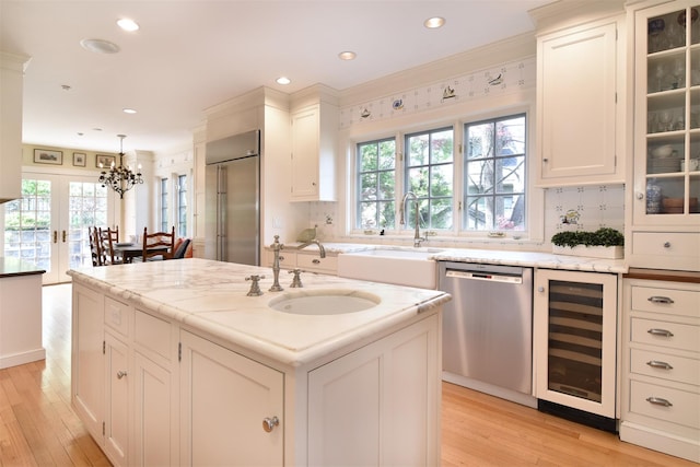 kitchen featuring a sink, appliances with stainless steel finishes, beverage cooler, and a healthy amount of sunlight