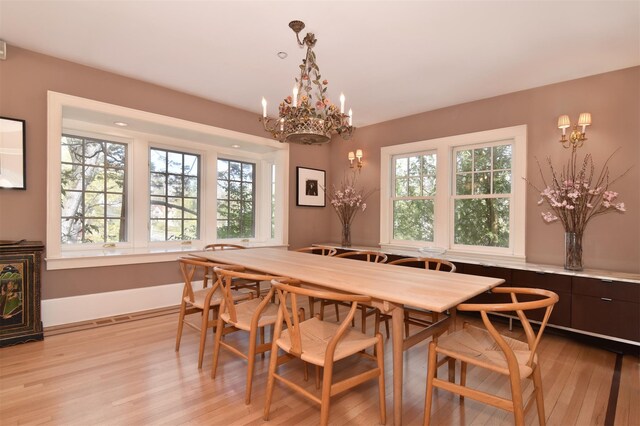 dining area featuring baseboards, a notable chandelier, and light wood finished floors