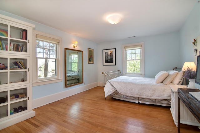 bedroom with light wood-style floors, baseboards, and visible vents