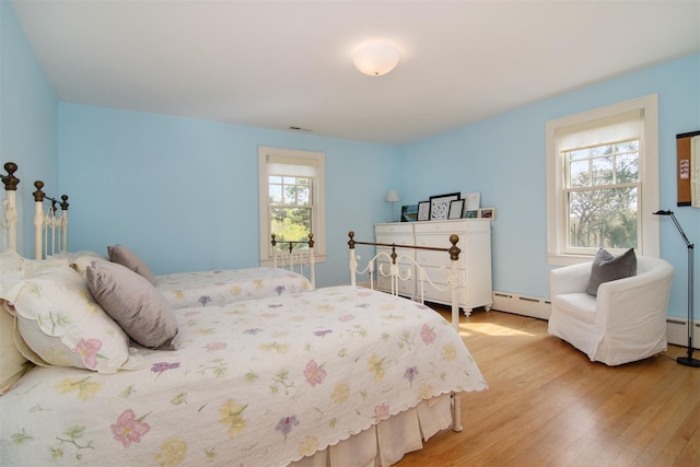 bedroom featuring a baseboard radiator, wood finished floors, and visible vents