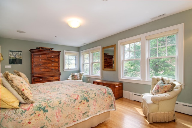 bedroom with visible vents, baseboard heating, and light wood-style floors