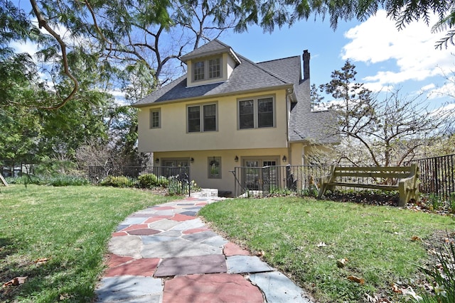view of front of property with a chimney, roof with shingles, fence, a front lawn, and stucco siding