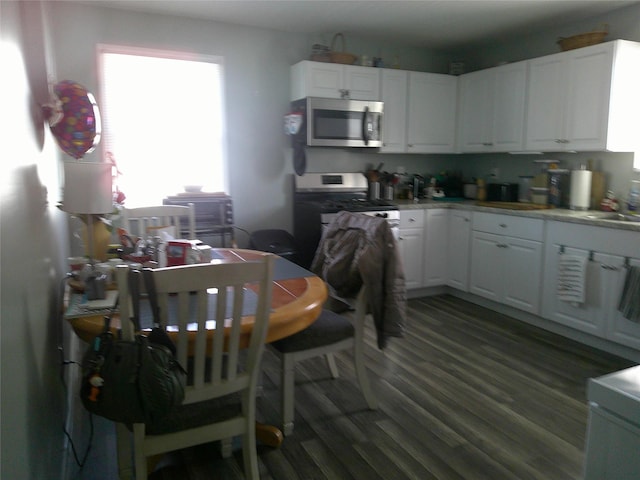kitchen with stainless steel appliances, white cabinets, dark wood-style flooring, and light countertops