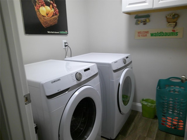 laundry area featuring washing machine and dryer, wood finished floors, and cabinet space
