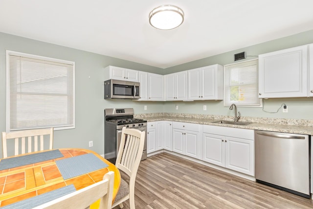 2 Lafayette Dr, Shirley, NY 11967 - kitchen with stainless steel appliances, white cabinetry, light wood finished floors, and light stone countertops