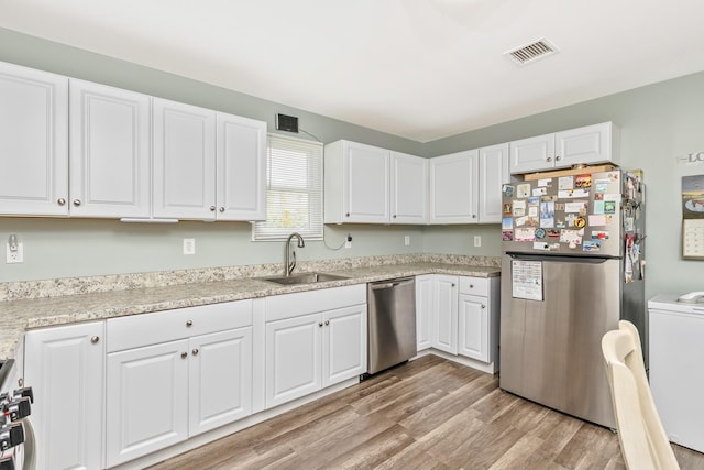 2 Lafayette Dr, Shirley, NY 11967 - kitchen featuring appliances with stainless steel finishes, white cabinetry, light wood-style flooring, and washer / clothes dryer
