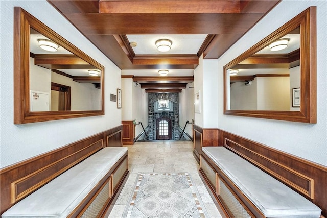 hall with crown molding, wood walls, and a wainscoted wall