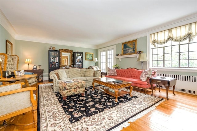 living area with crown molding, radiator heating unit, and wood finished floors