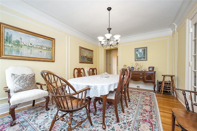 dining area featuring crown molding, light wood-style flooring, and a chandelier