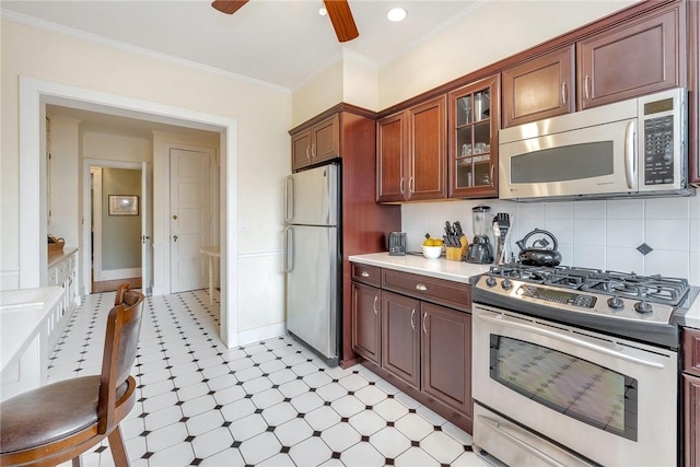 kitchen with ornamental molding, glass insert cabinets, light floors, light countertops, and appliances with stainless steel finishes