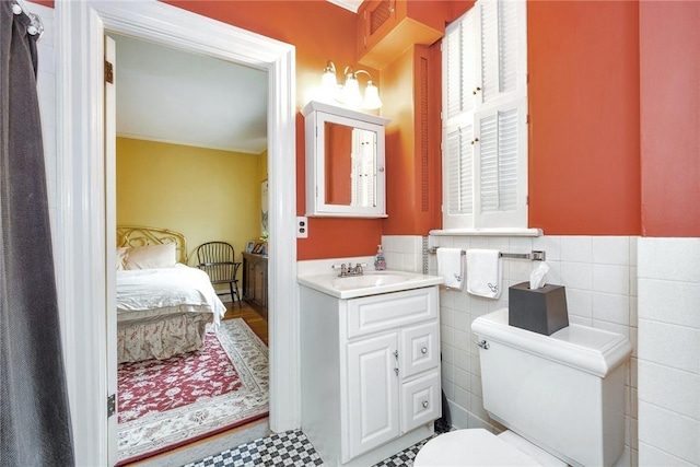bathroom featuring vanity, ensuite bath, toilet, and tile walls