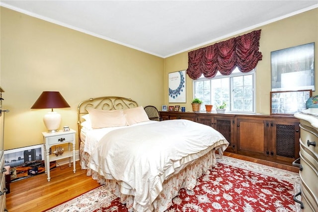 bedroom featuring ornamental molding and wood finished floors