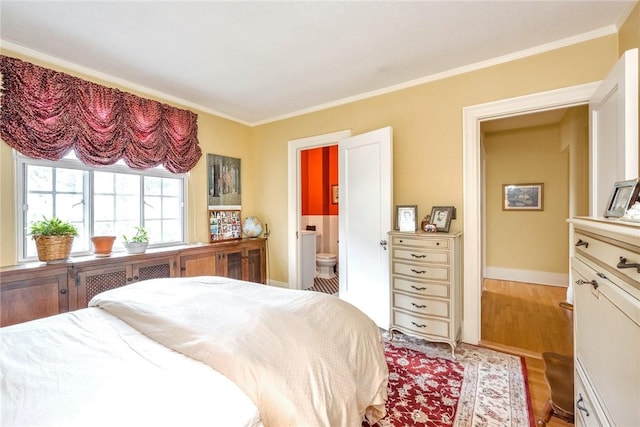 bedroom with baseboards, ornamental molding, wood finished floors, and connected bathroom