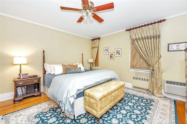 bedroom featuring crown molding, radiator, wood finished floors, baseboards, and a ceiling fan