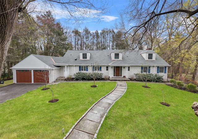 cape cod house featuring an attached garage, aphalt driveway, roof with shingles, and a front yard