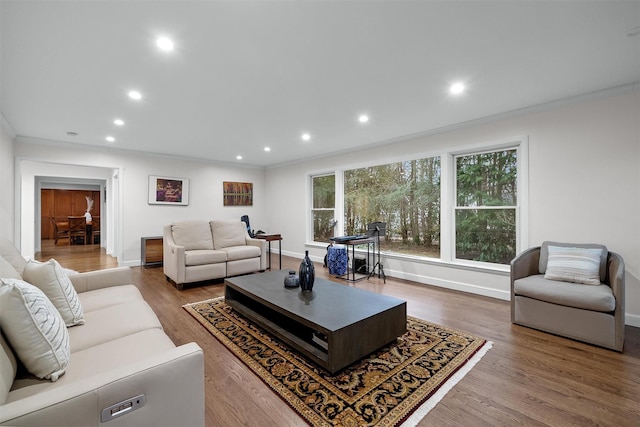 living room featuring baseboards, ornamental molding, wood finished floors, and recessed lighting