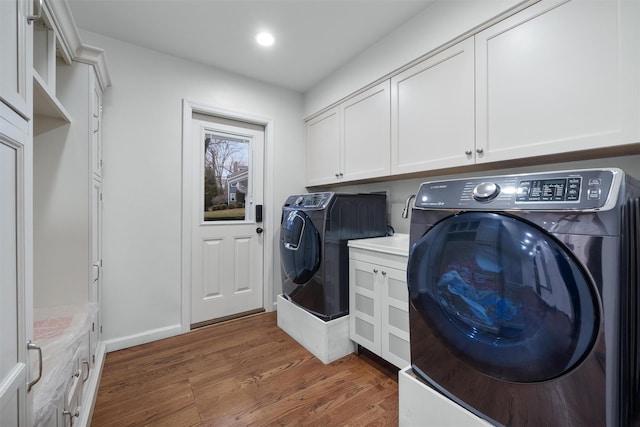 washroom with cabinet space, wood finished floors, washer and clothes dryer, and recessed lighting