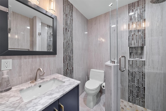 bathroom with tile walls, toilet, vanity, and a stall shower