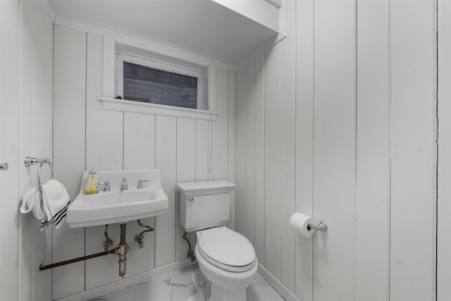 half bath featuring marble finish floor, a sink, and toilet