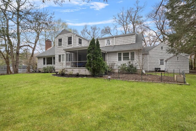 rear view of house with fence, a lawn, a chimney, and a sunroom