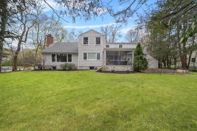 back of house with a yard, a sunroom, a shingled roof, and a chimney