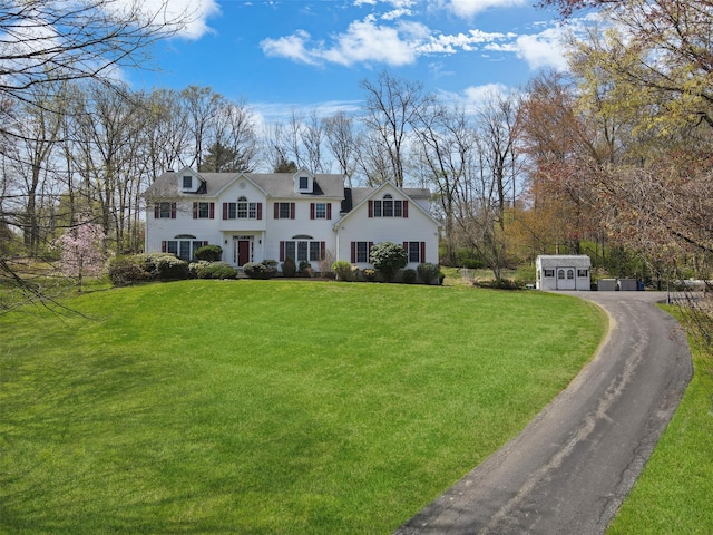 view of front facade with a front lawn, aphalt driveway, and an outbuilding