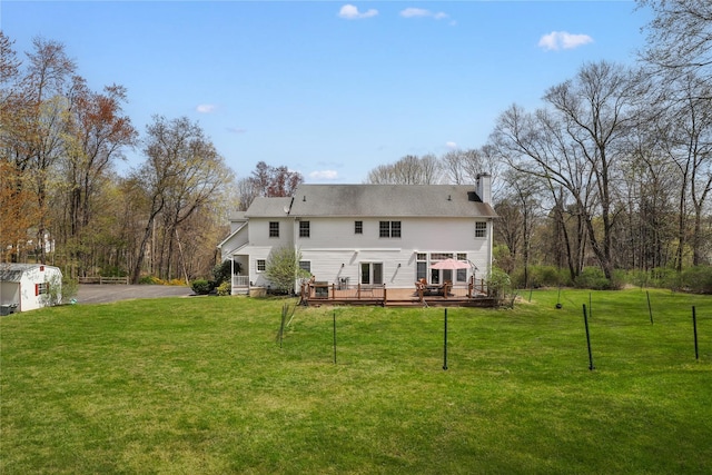 back of property with a wooden deck, a lawn, and a chimney