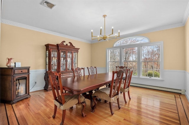 dining area with an inviting chandelier, visible vents, ornamental molding, light wood-style flooring, and baseboard heating