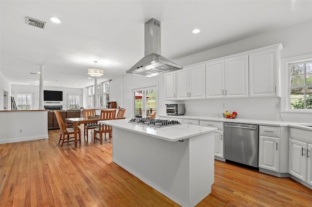 kitchen featuring light wood finished floors, stainless steel appliances, visible vents, island range hood, and white cabinetry