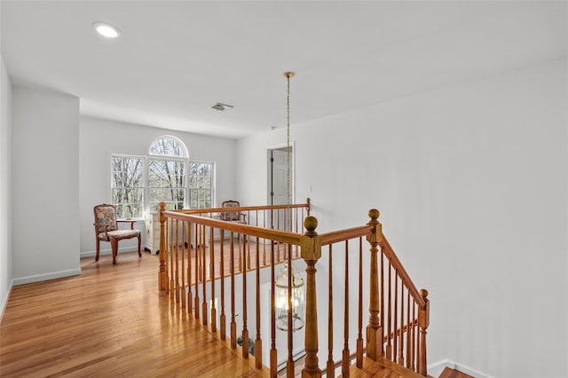 hallway featuring recessed lighting, wood finished floors, visible vents, and an upstairs landing