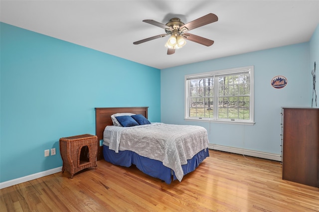 bedroom featuring light wood-type flooring, baseboard heating, baseboards, and ceiling fan