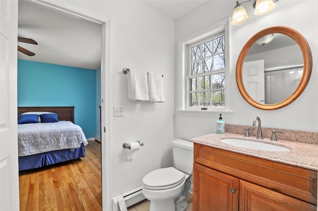 bathroom with wood finished floors, a baseboard heating unit, connected bathroom, vanity, and toilet